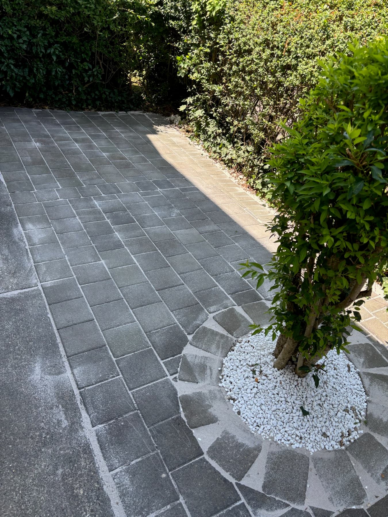 Terrasse aus dunklem Pflaster mit Zypressen und Kiesbeet