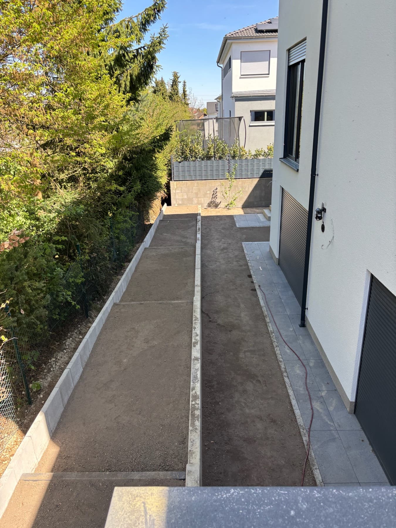 Kiesweg am Haus entlang mit Zaun